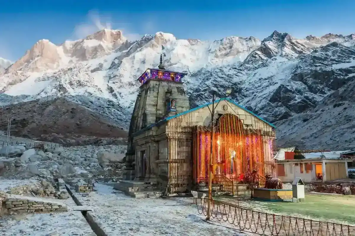 Kedarnath Temple illuminated at dusk with snow-capped Himalayas in the background